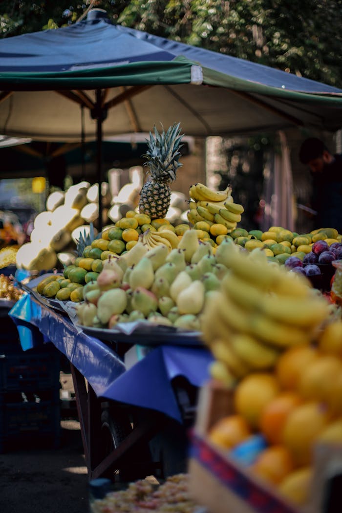 Colorful outdoor market stall showcasing a variety of fresh fruits under a sunny sky.